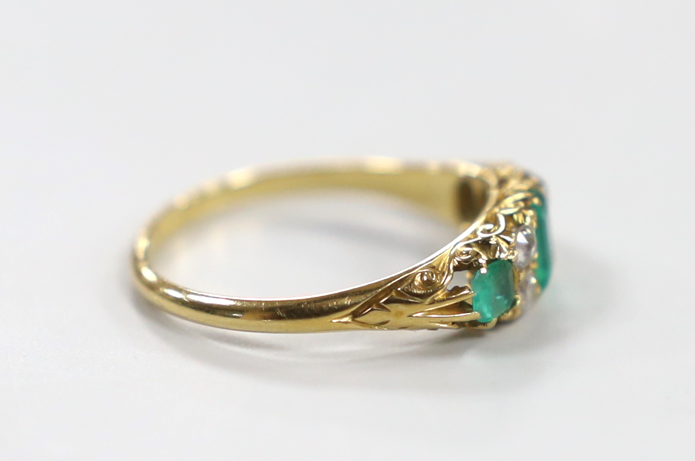 A late Victorian 18ct gold, three stone emerald and four stone diamond spacer set half hoop ring, size P/Q, gross weight 3.5 grams.